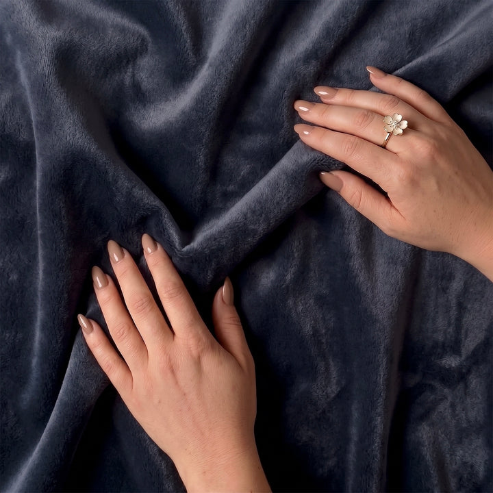 Hands touching midnight charcoal blue minky sherpa fleece freak sheet with a floral ring on one finger