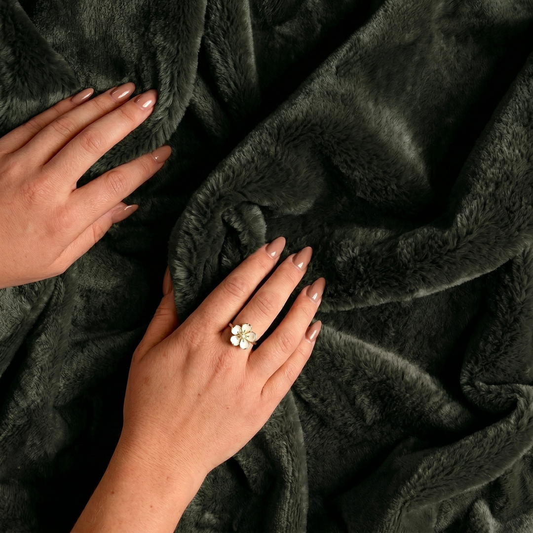 Close-up of hands on  forest color luxury plush fleece freak sheet with a floral ring.