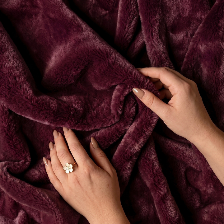 Close-up of hands holding a plum color luxury plush fleece freak sheet
